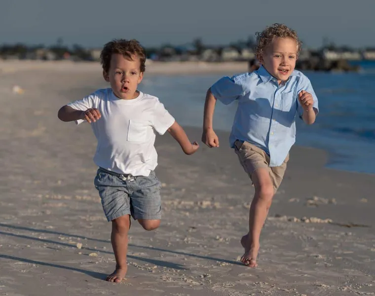 Two children running along the shoreline in golden evening light