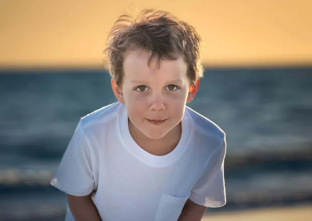 Child backlit by warm golden sunset light on the beach