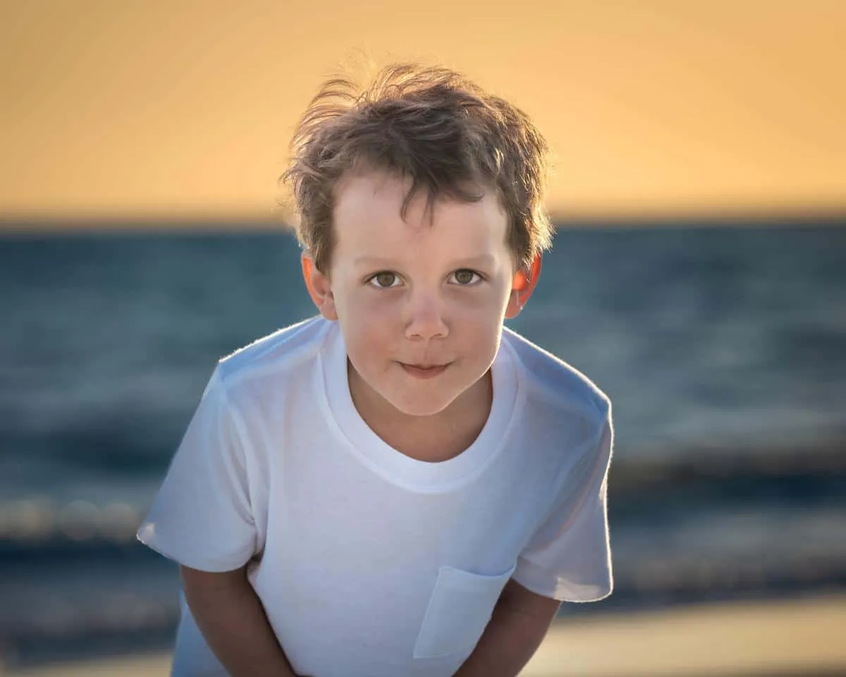 Child backlit by warm golden sunset light on the beach