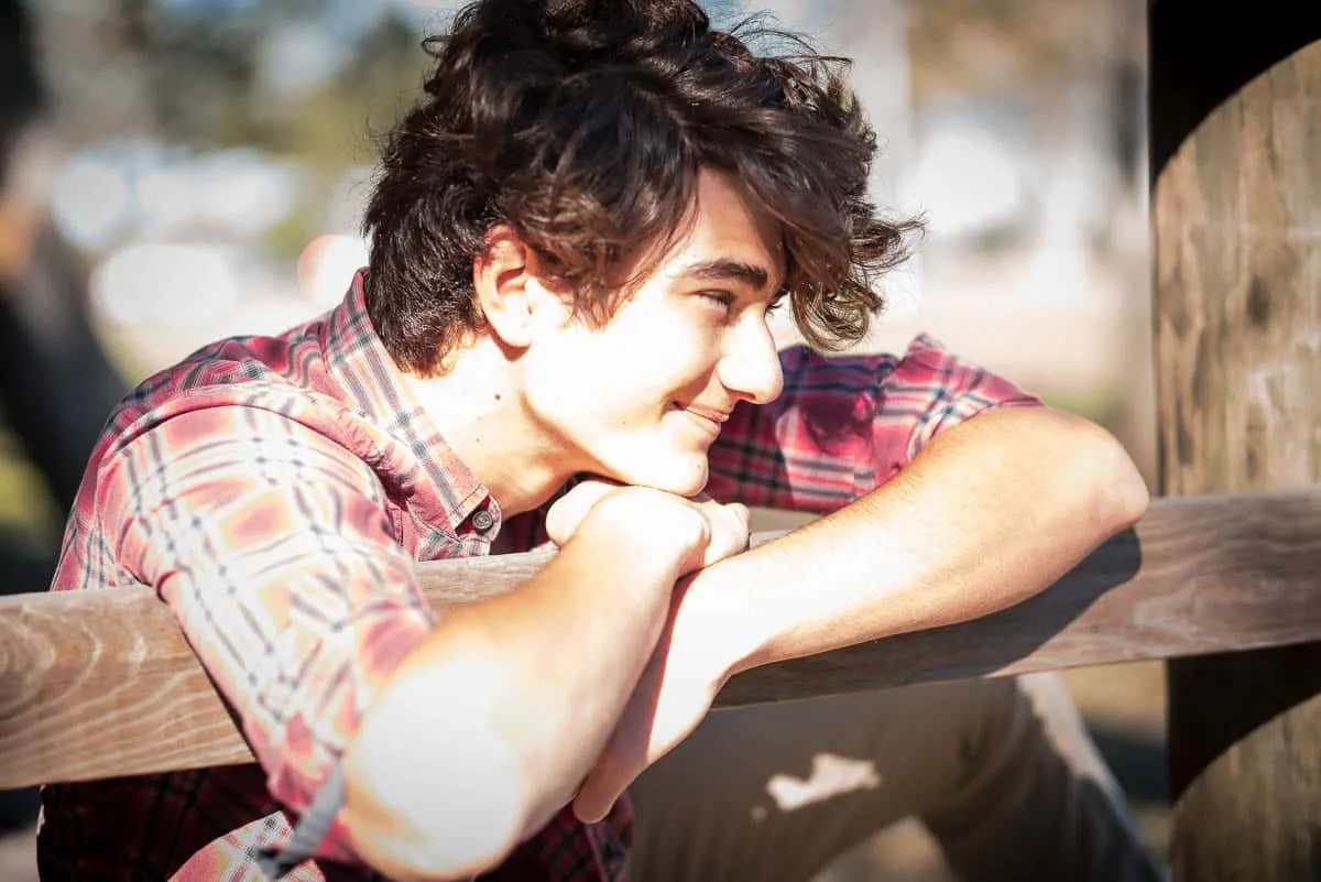 High school senior posing with his dog in a wooded area near Sarasota