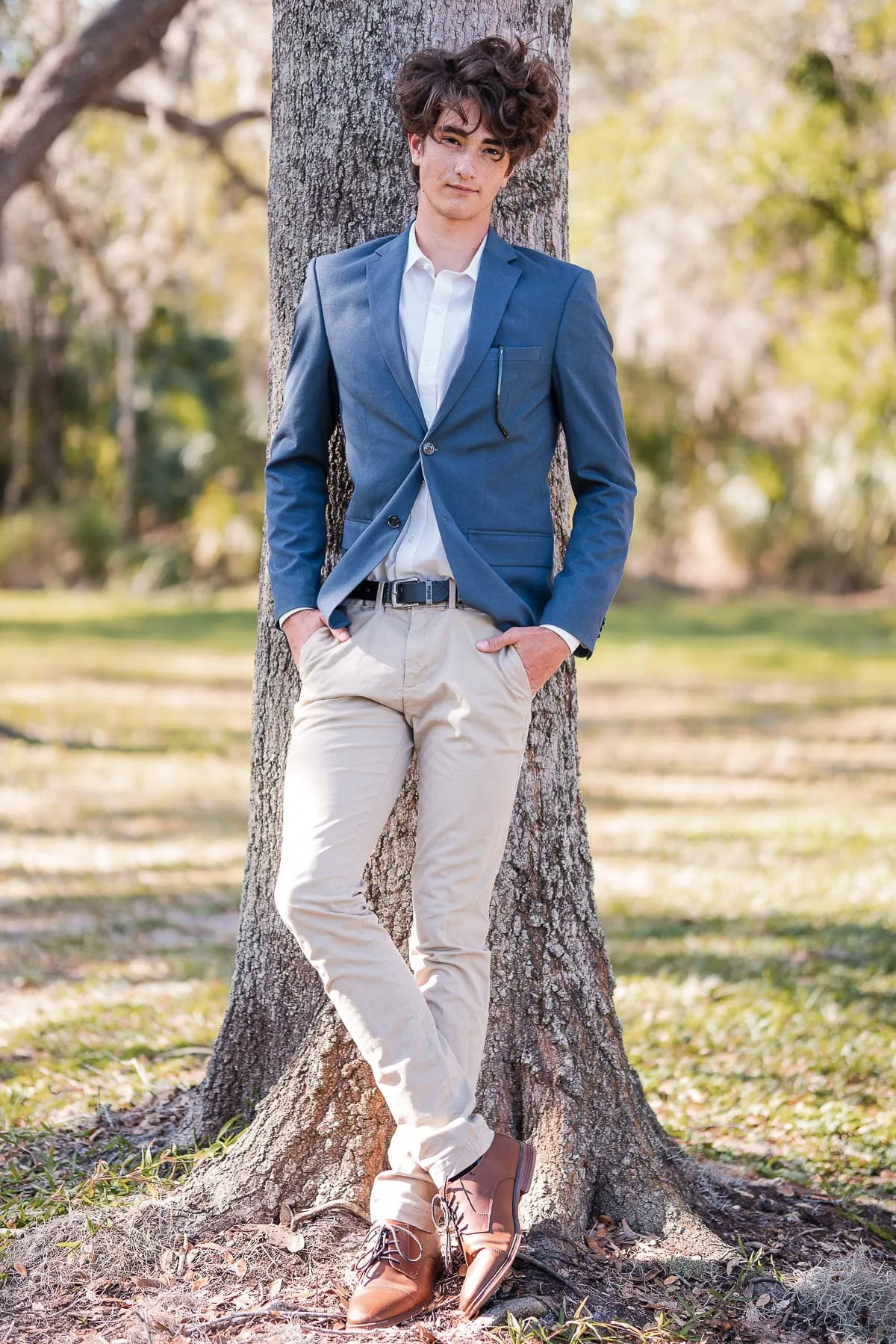 High school senior posing with his dog in a wooded area near Sarasota