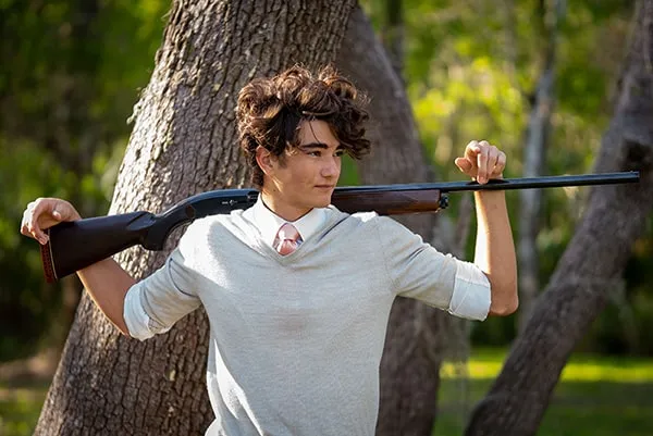High school senior posing with his dog in a wooded area near Sarasota
