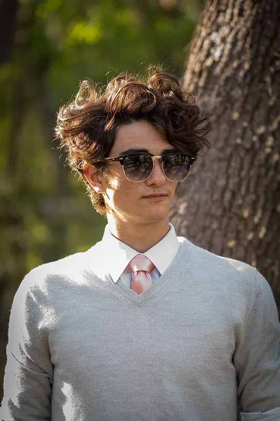 High school senior posing with his dog in a wooded area near Sarasota
