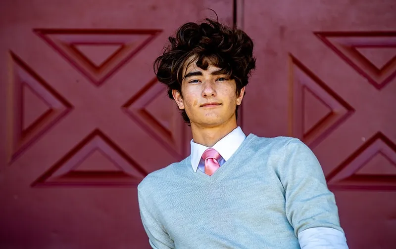 High school senior posing with his dog in a wooded area near Sarasota