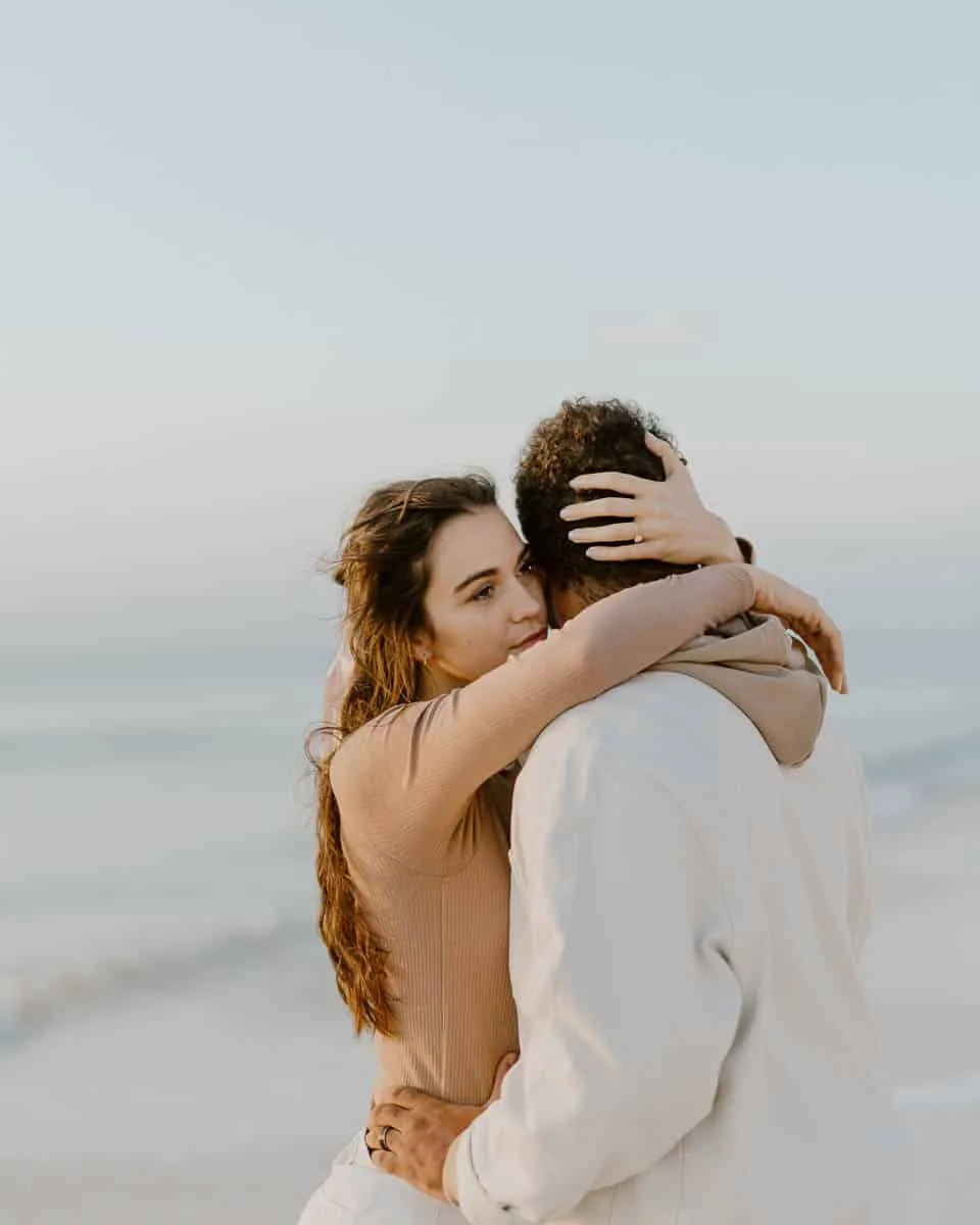 Couple walking together along Siesta Beach on a cool, hazy day