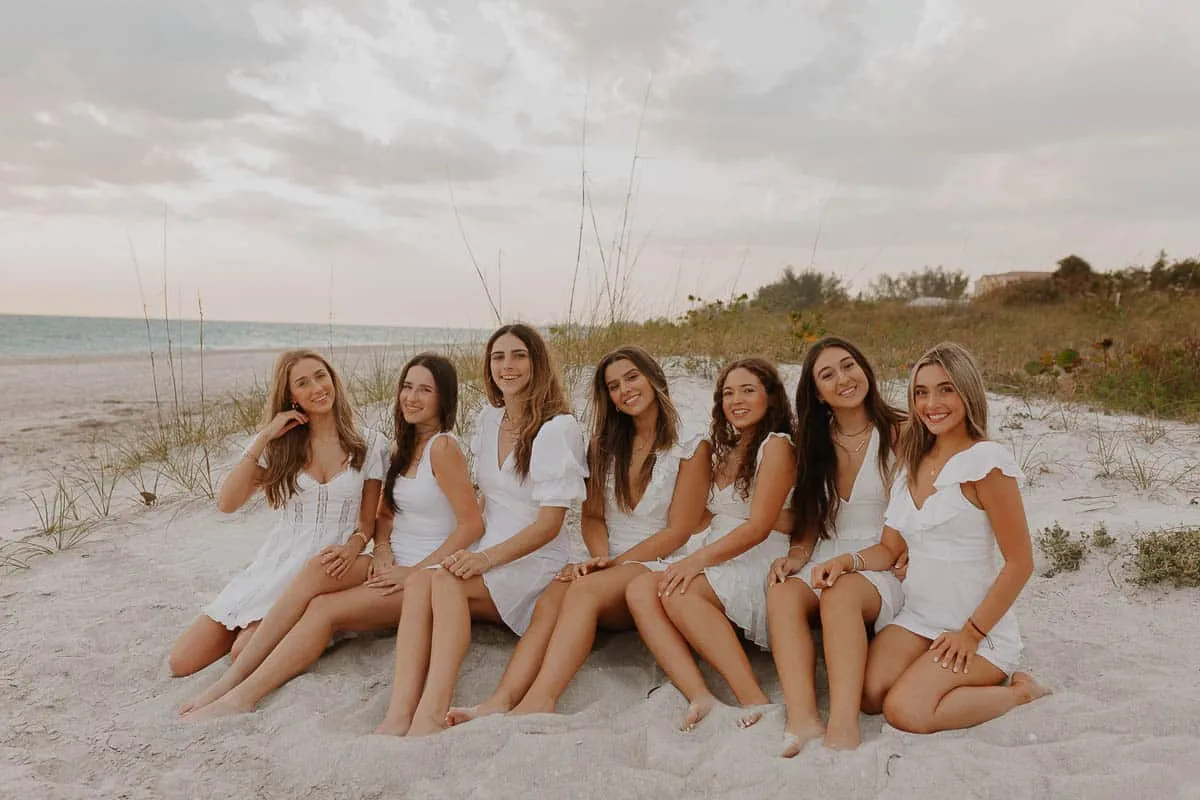 Group of graduating senior girls laughing together on the beach at Siesta Key