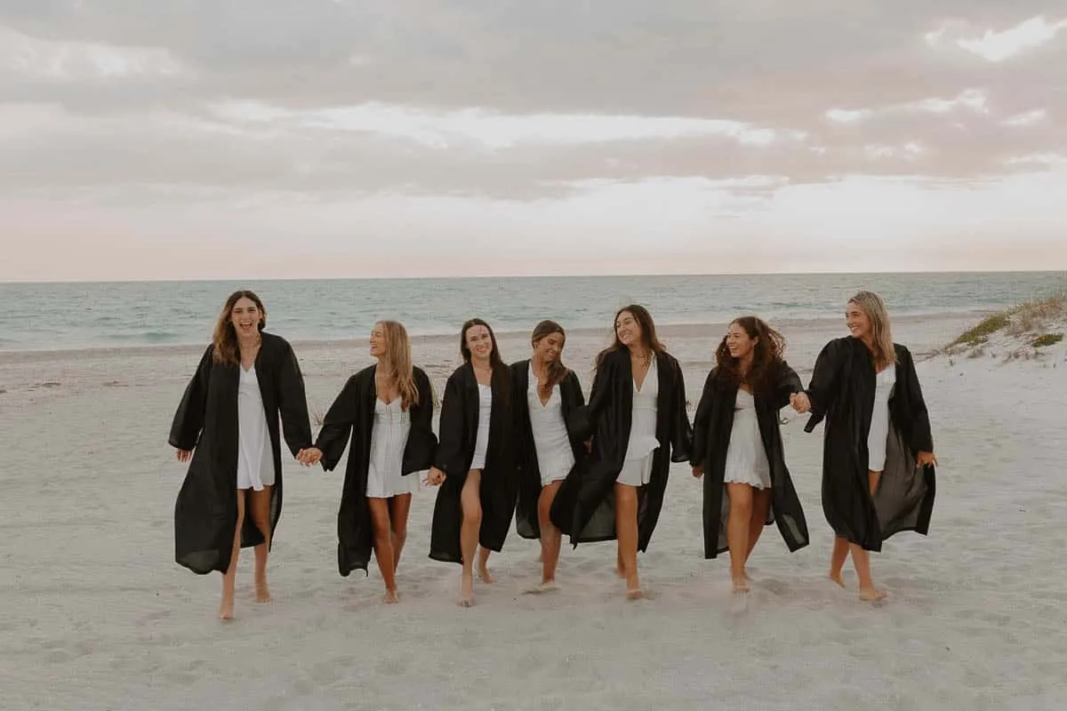 Group of graduating senior girls laughing together on the beach at Siesta Key