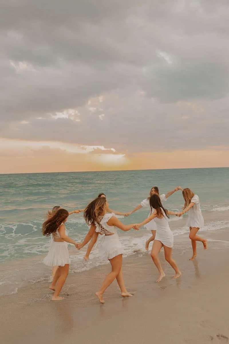 Group of graduating senior girls laughing together on the beach at Siesta Key