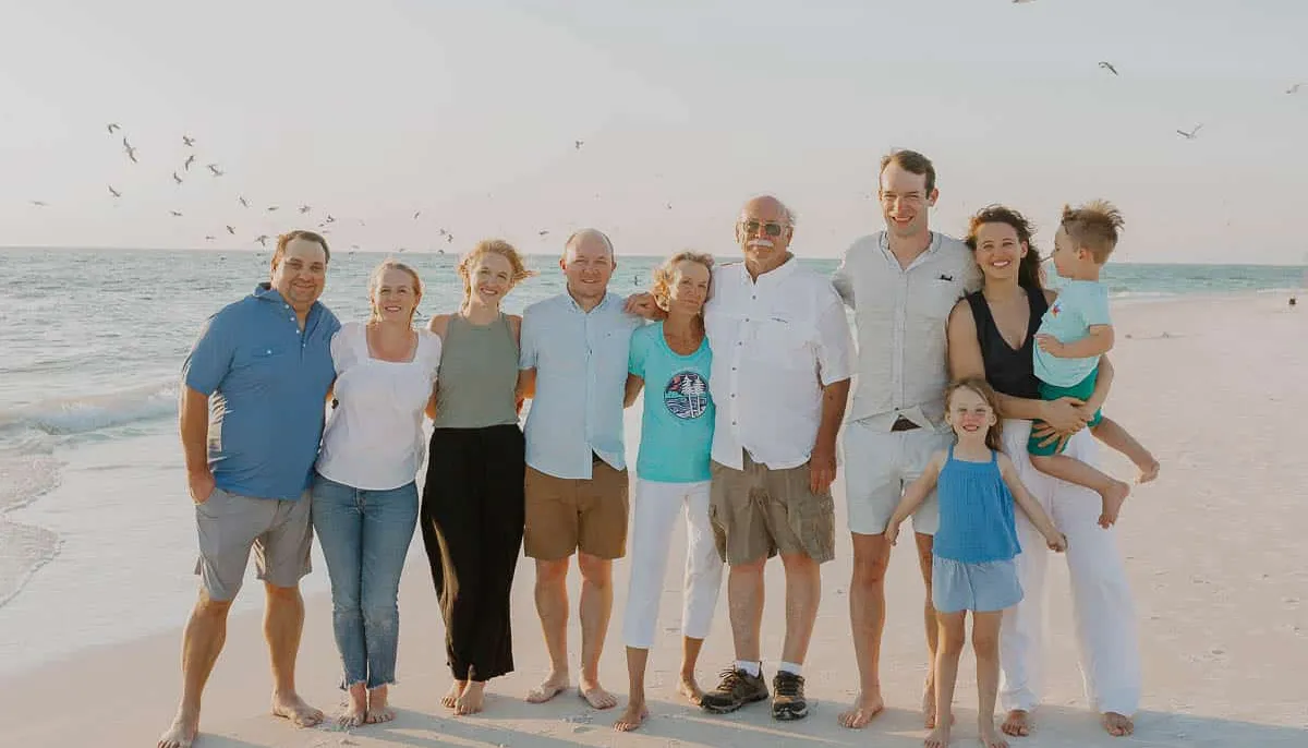 Three generations of a family standing together on the beach at sunset