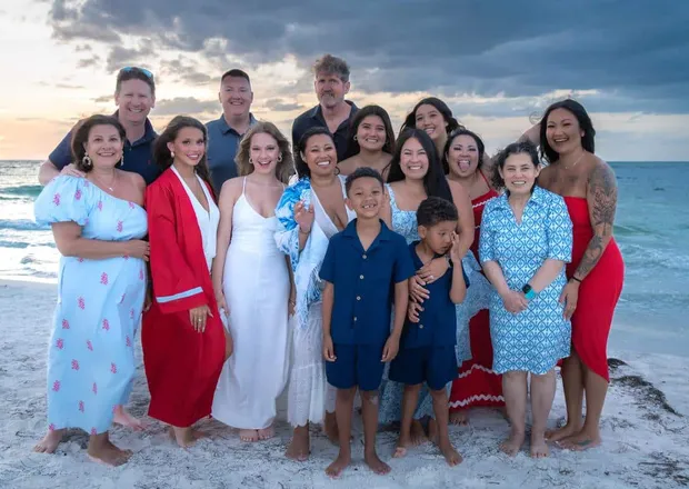 Large extended family gathered together on the beach at sunset