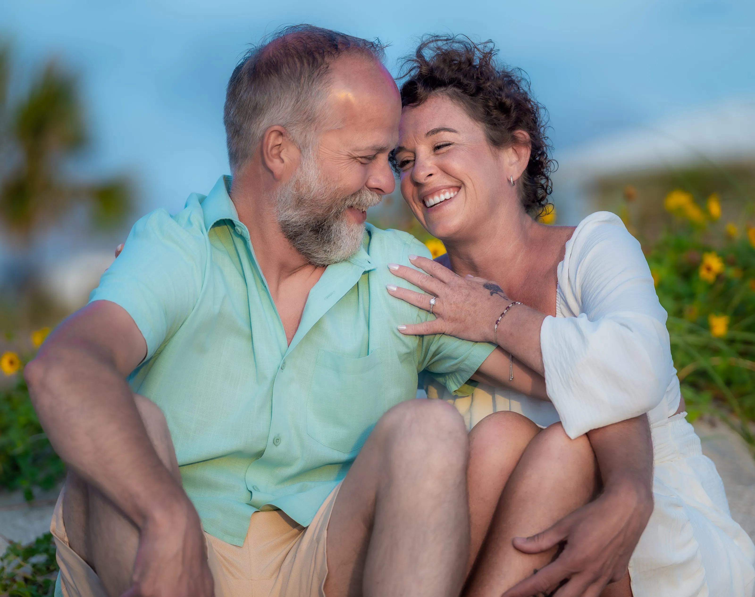 Couple laughing cheek to cheek among the dune sunflowers